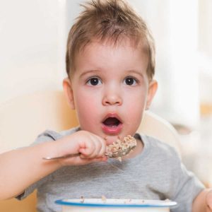 little boy eating buckwheat cereal porridge