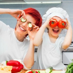 mom and daughter with cucumber and peppers by their eyes cooking in the kitchen for healthy eating behaviors - SuperKidsNutrition.com
