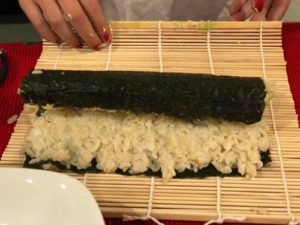 step to make sushi by rolling the seaweed with the bamboo