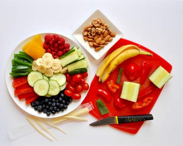 prepping ingredients for food art with fruits, veggies, and nuts on cutting board and plate