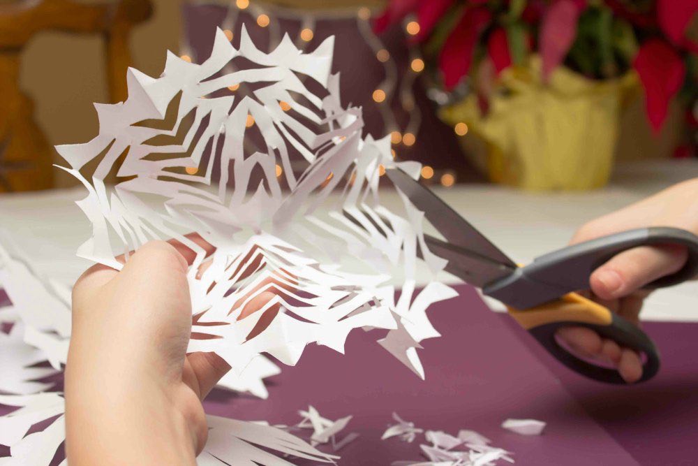 kid making snowflake out of paper 