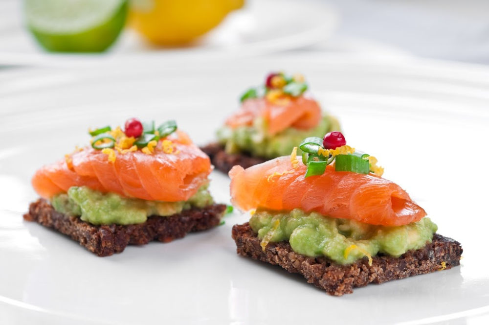 Brown bread sandwich with smoked salmon, avocado topped with chive and pepper