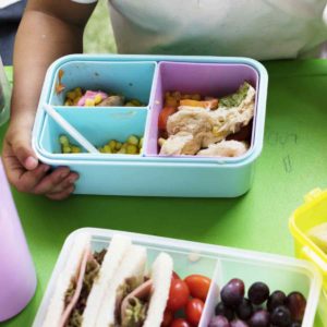 Kids eating environmentally friendly lunch at elementary school with trash free lunch box