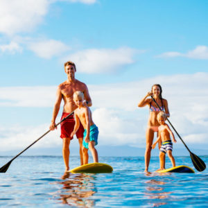 Family Having Fun Stand Up Paddling Together in the Ocean on Beautiful Sunny Morning