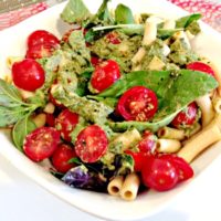 chickpea pasta with cherry tomatoes, basil, and sauce in a white bowl