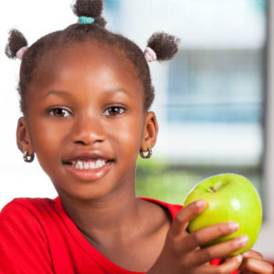 African girl at school snacking on an apple for a healthy snack