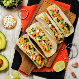 Shrimp tacos with avocado salsa on wood background. toning. selective focus