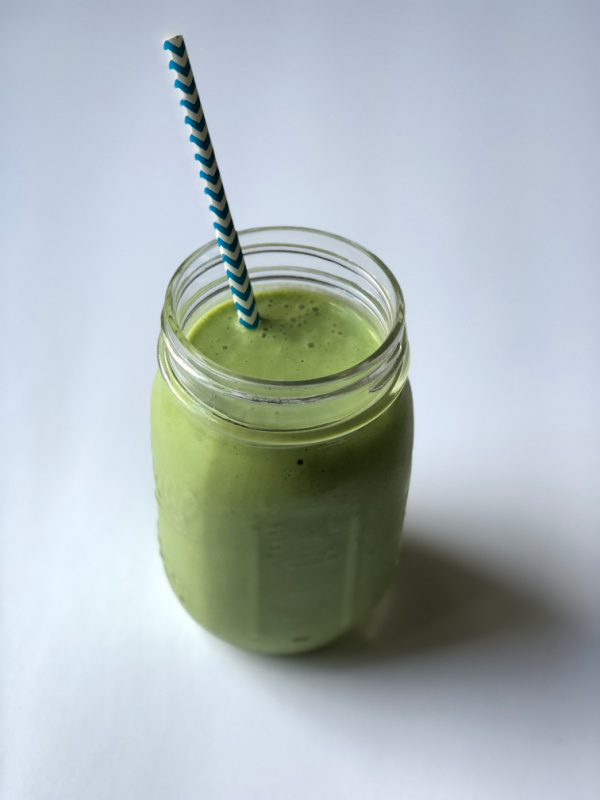 green smoothie with striped straw in mason jar