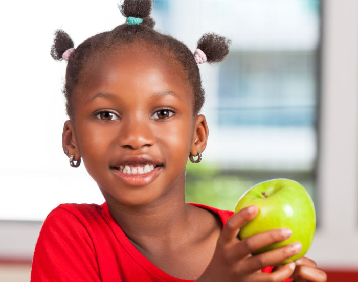 African girl at school with apple in hand.