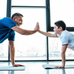 father and son doing high five sign while doing push up exercise for indoor games for kids