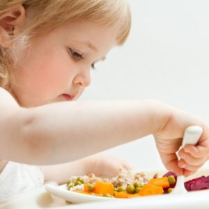 Adorable baby girl picky eater eating fresh vegetables; healthy eating for a baby