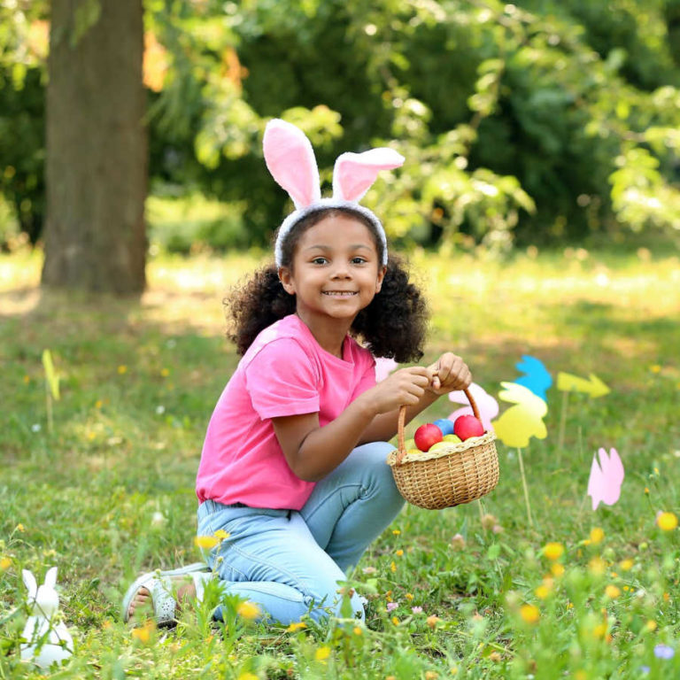 little girl collecting eggs in her easter basket