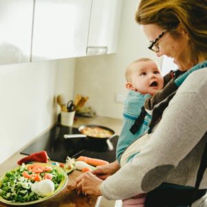 breastfeedinbreastfeeding snacks mom making a salad with baby in kitchen