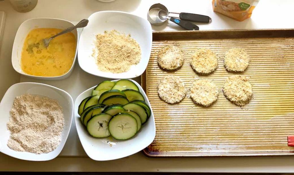 process of making zucchini chips with egg, breadcrumbs, and flour