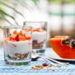 healthy greek yogurt and papaya parfait in glasses. Outdoor background.