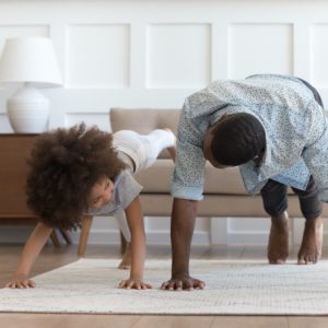 African father and little daughter do push-up exercise indoors